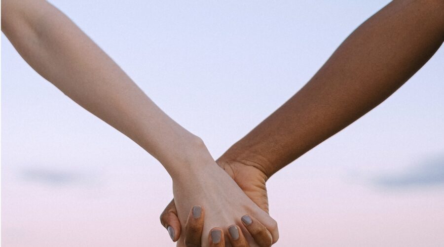 Couple holds hands on beach during sunset